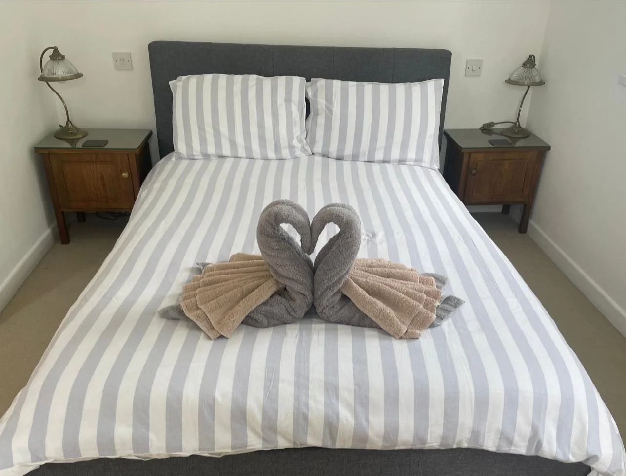 folded swan towels on bed